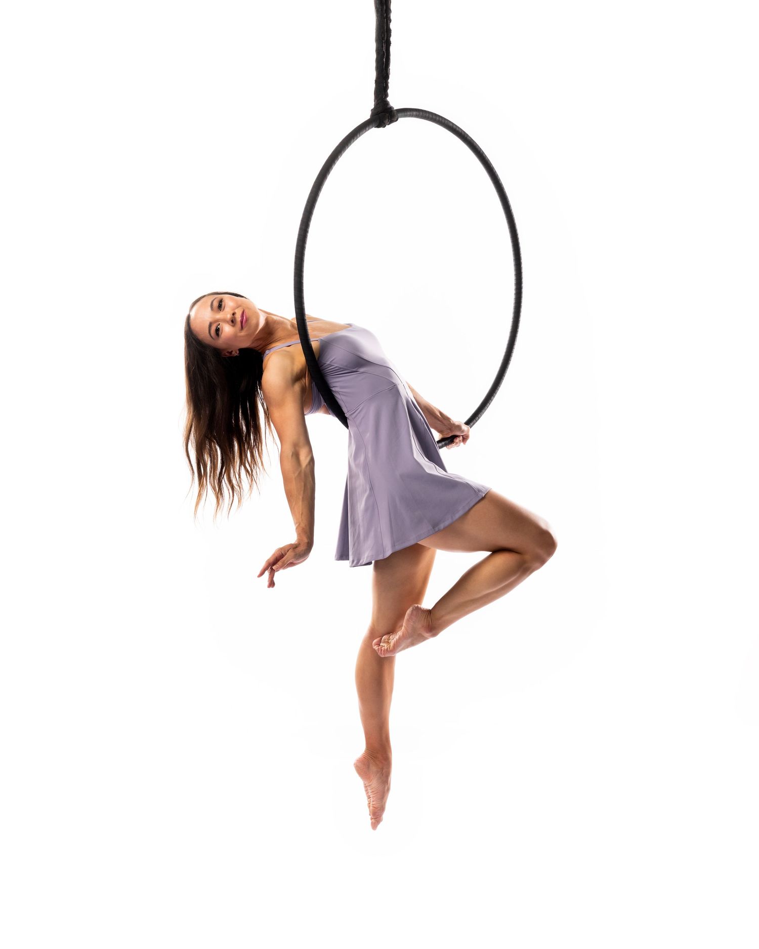 Aerial hoop performer moving with control and beauty — photography capturing the essence of aerial performance on a white backdrop.