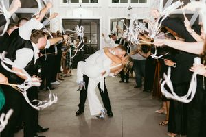 Wedding guests throw white paper airplanes at the newlywed couple during their ceremony exit celebration.