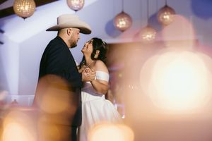 A couple dancing under glowing disco balls at a wedding reception in a dimly lit venue.