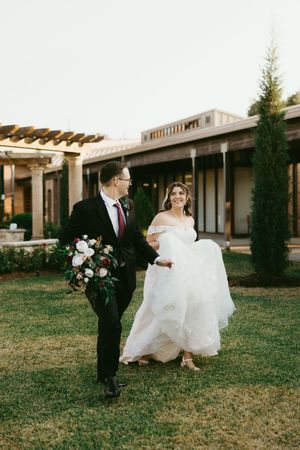 A bride and groom walk together on a grassy lawn outside a modern building in a romantic wedding photo sequence.