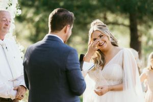 A bride and groom share an intimate moment during their outdoor wedding ceremony surrounded by natural scenery.