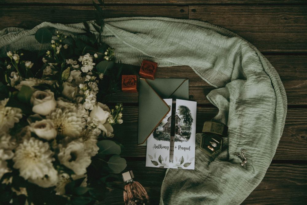 Vintage styled flatlay of dried flowers, old photographs, and fabric on rustic wooden background.