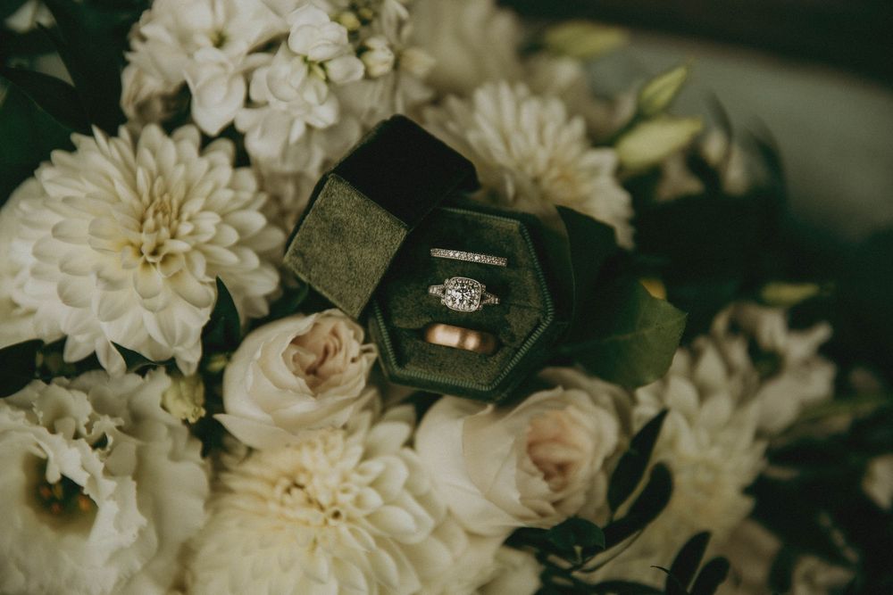 Wedding rings nestled among white dahlias and roses in a romantic floral arrangement.