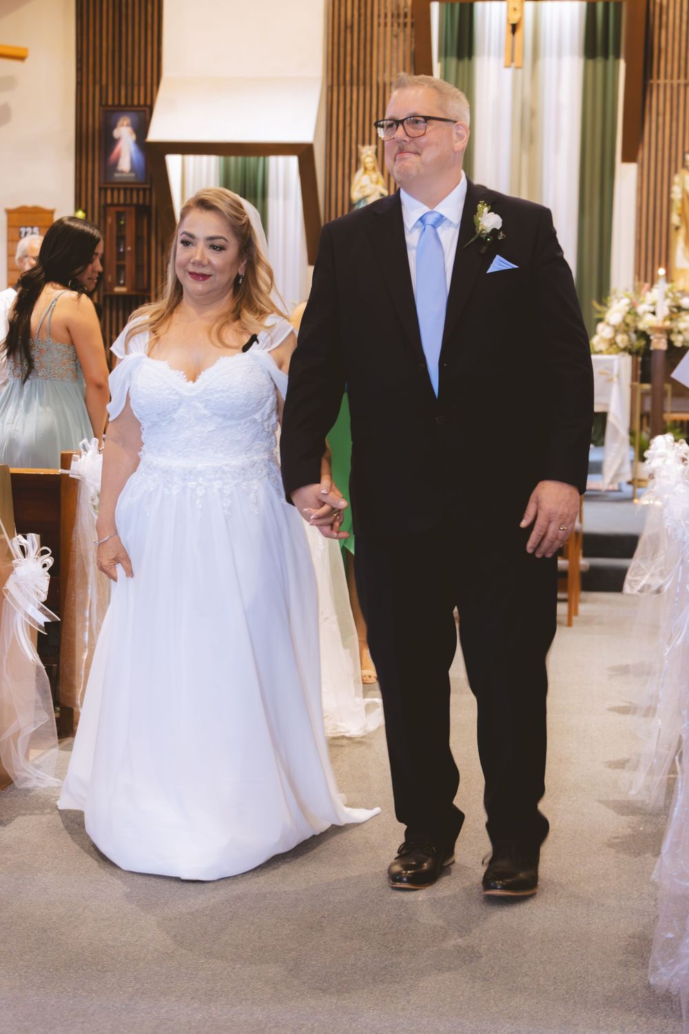 Newlywed couple walks hand in hand down church aisle after completing their wedding ceremony.