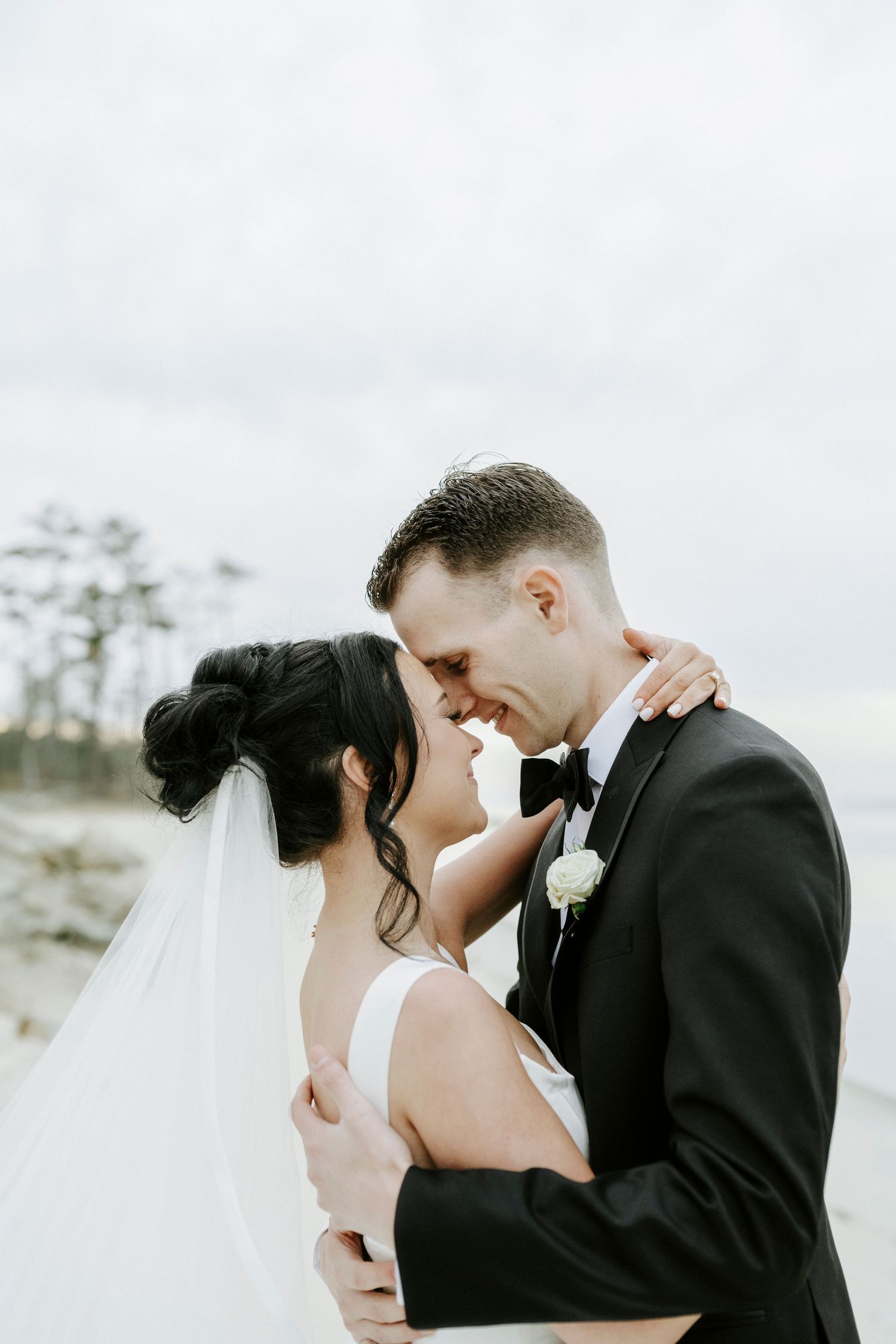 A romantic wedding moment captured against a bright, airy beach backdrop.