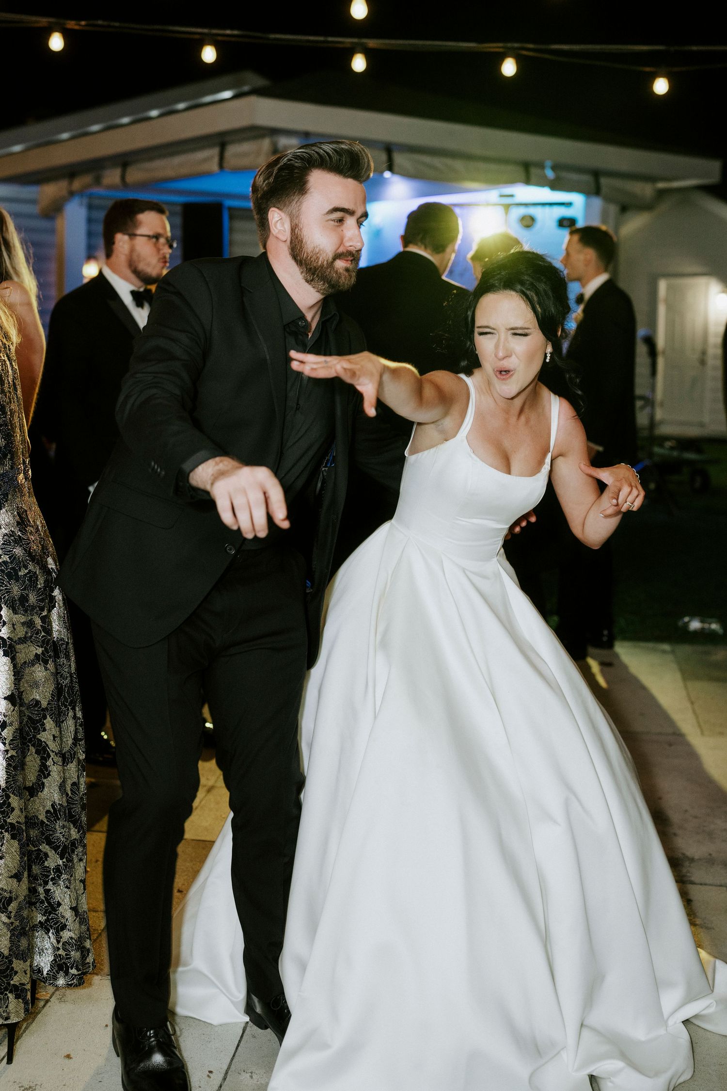 Wedding reception dance floor filled with guests in formal attire enjoying the celebration.