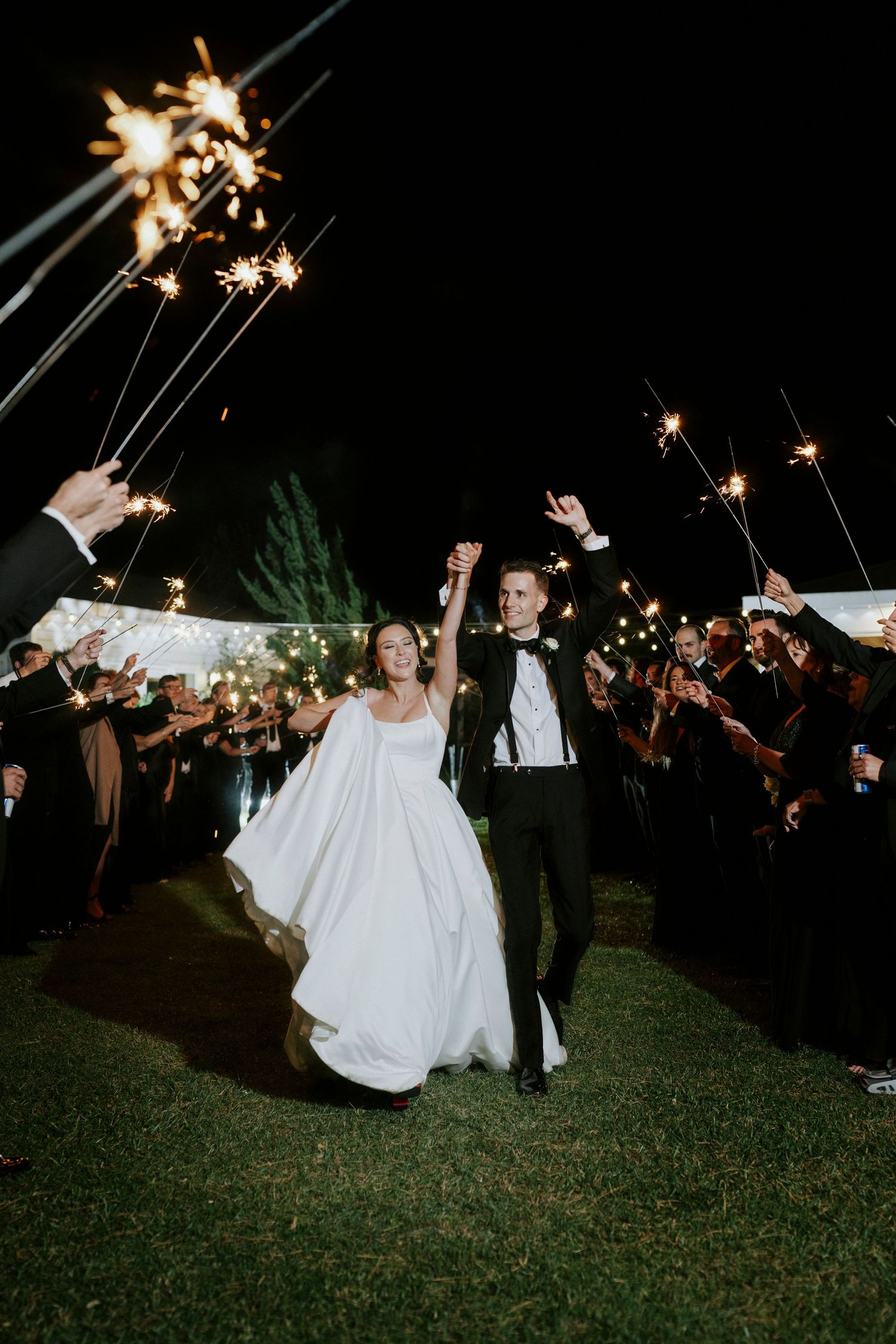 Wedding sparkler exit at night with guests creating a magical light tunnel for the celebration.