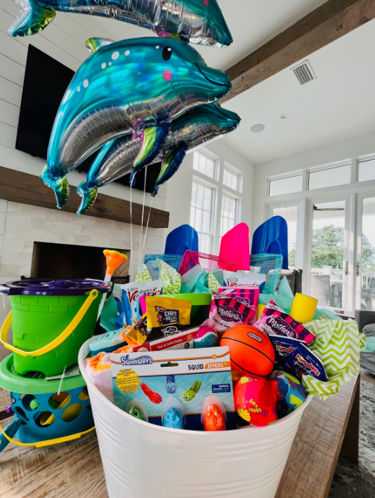 Colorful party decorations featuring large teal dolphin balloons and festive accessories arranged in a bright indoor space.