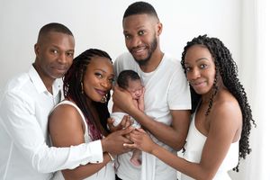 A group poses together wearing coordinated white outfits against a white background for a stylish portrait session.