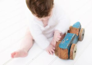 A small wooden toy car rolls across a white surface, creating a sequence of movement in multiple frames.
