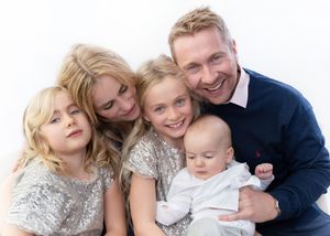 A loving family group cuddles together in a candid black and white portrait against a white background.