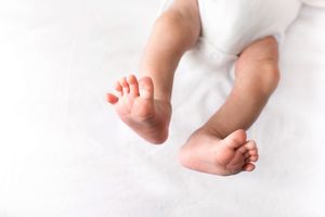 Two tiny baby feet resting on a soft white blanket.