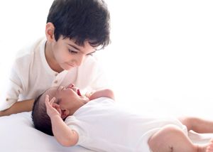 Two people share a tender romantic moment lying down together on white bedding.