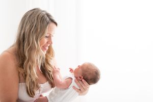 A series of tender moments between a parent and baby in white clothing against a light background.