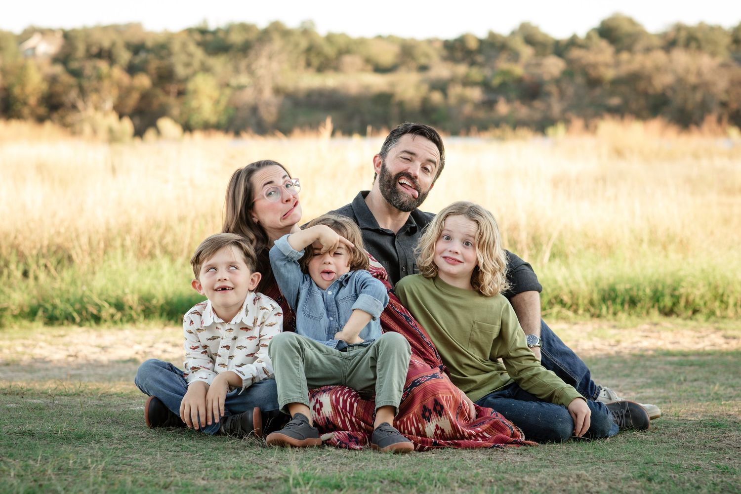 family sitting at Brushy Creek Lake Park making silly faces during their sunset family mini session in fall.