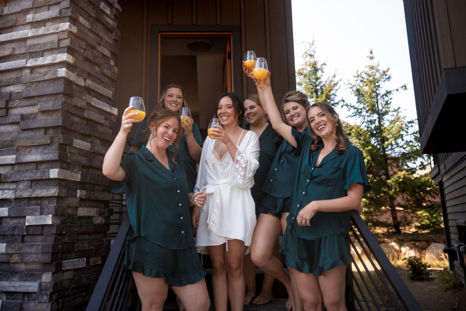 Wedding party celebrating outdoors during golden hour near stone building.