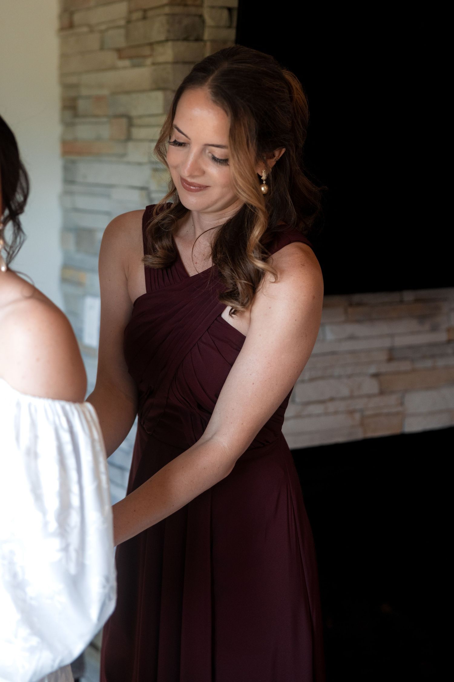 Person in burgundy dress making final adjustments before the ceremony.