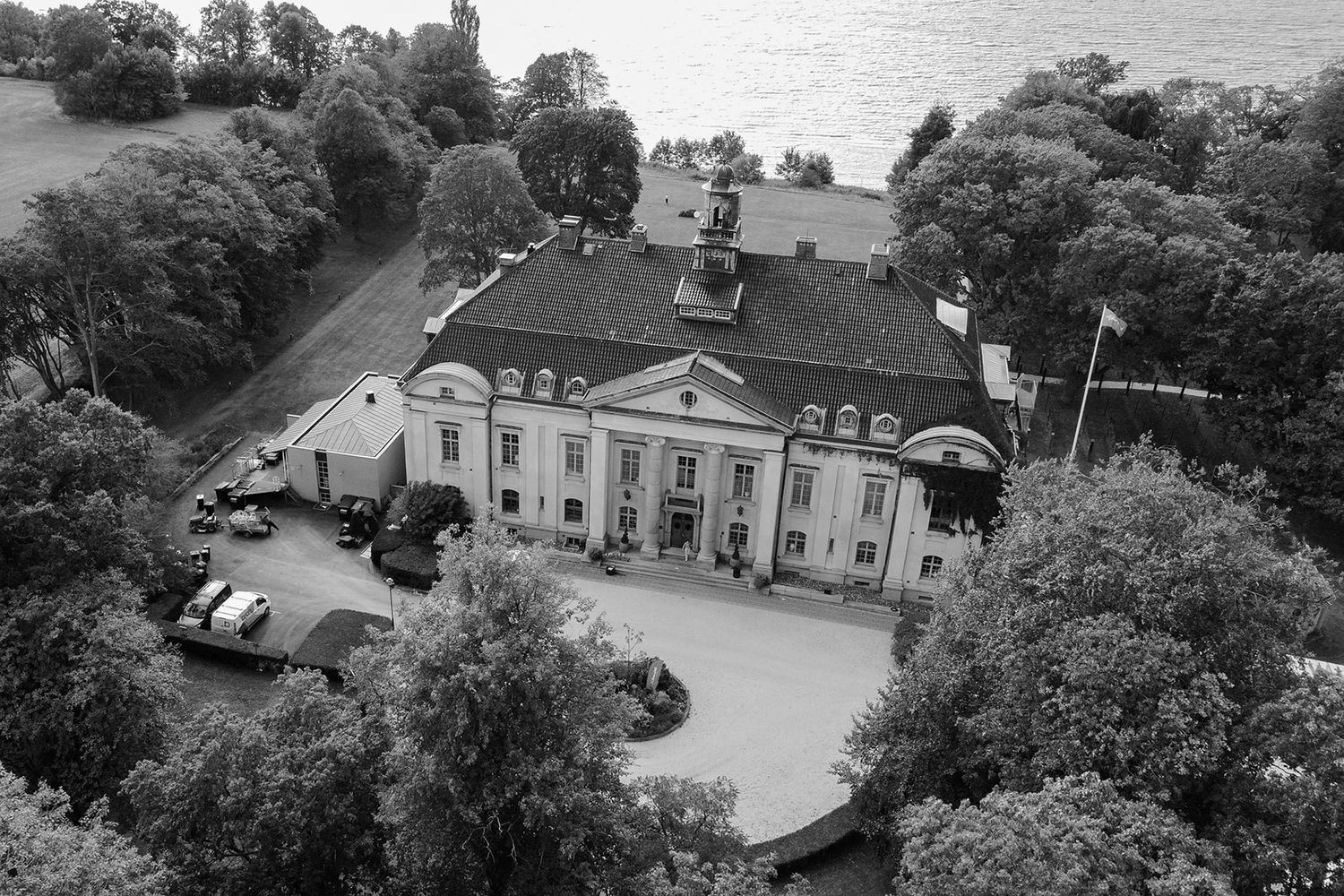 Aerial view of historic mansion estate with manicured grounds and circular driveway surrounded by lush trees.