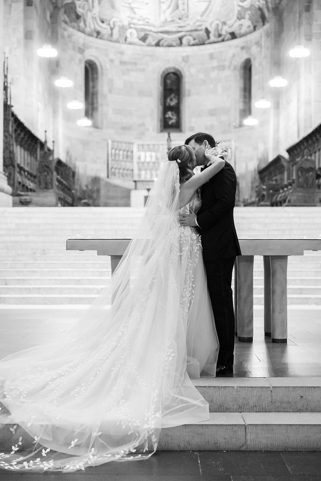 A romantic black and white wedding photo series showing a couple embracing on church steps in elegant attire.
