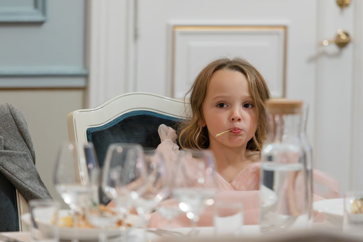 A person blowing out candles on a birthday cake at a white dining table.