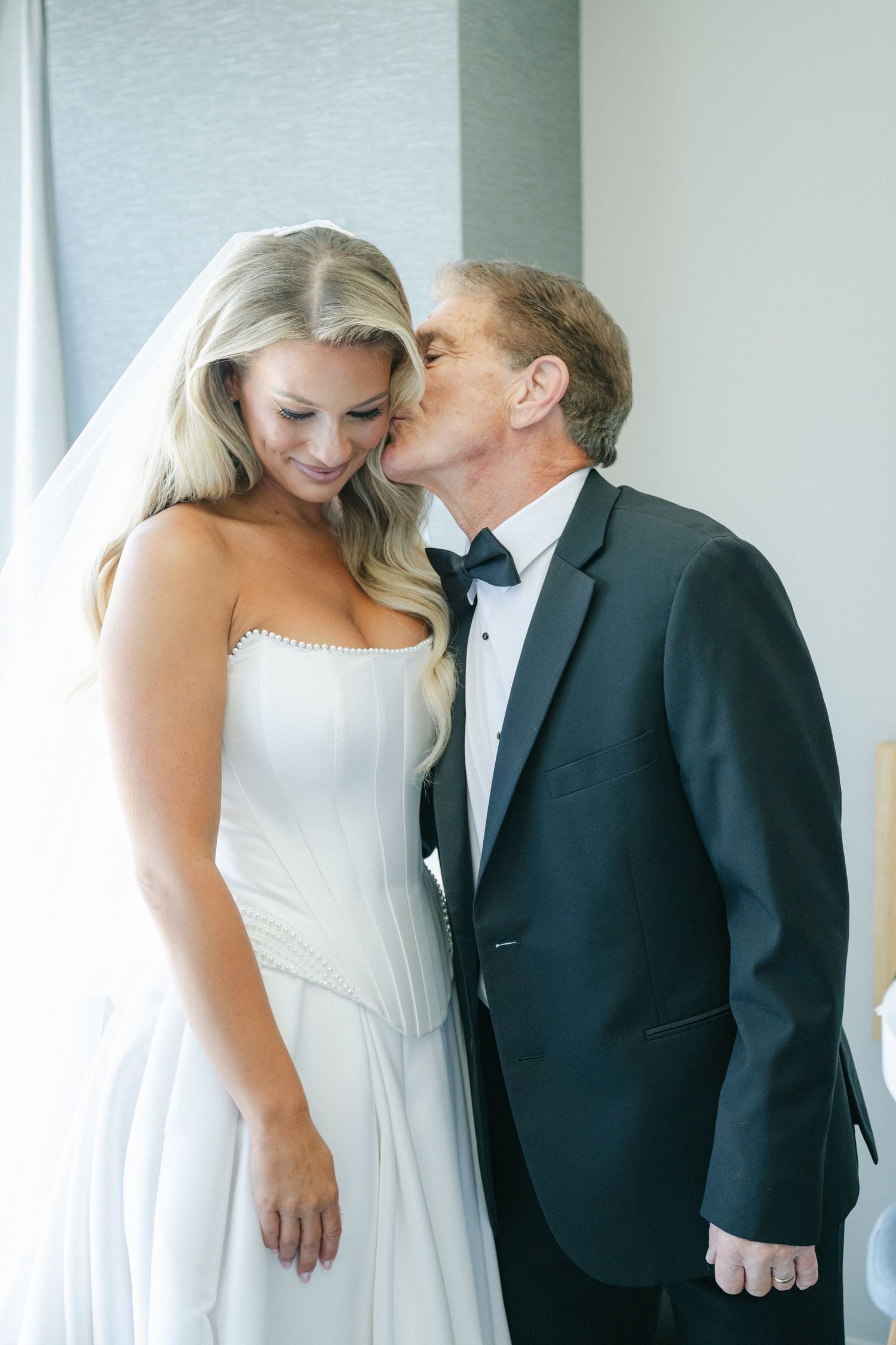 A romantic wedding photo series showing tender moments between a couple in formal attire against a light background.