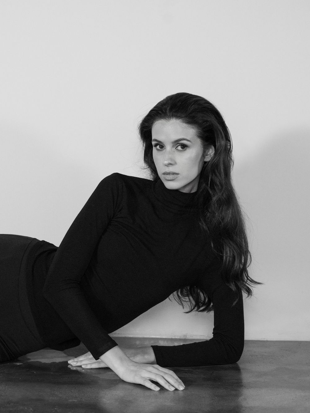 A series of artistic black and white portraits showing a figure in a black turtleneck reclining on a floor.