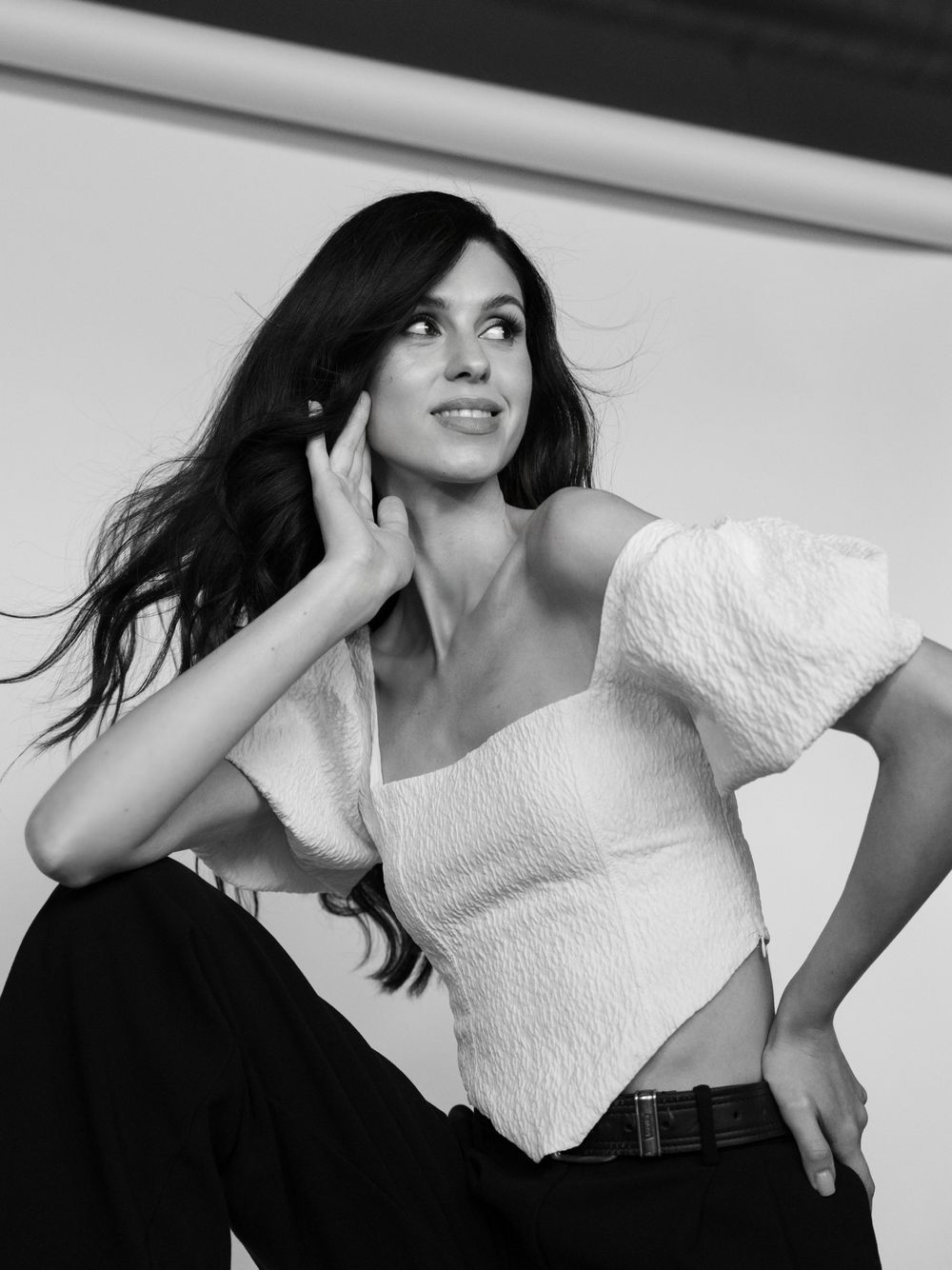A black and white photo series showing a person in a white top posing dynamically against a light background.