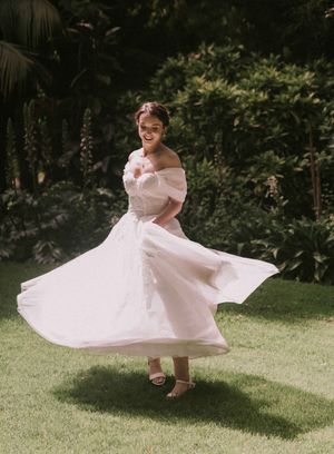 A young person in a pink dress twirls joyfully on a grassy lawn in a flowing dress creating a circular motion effect.