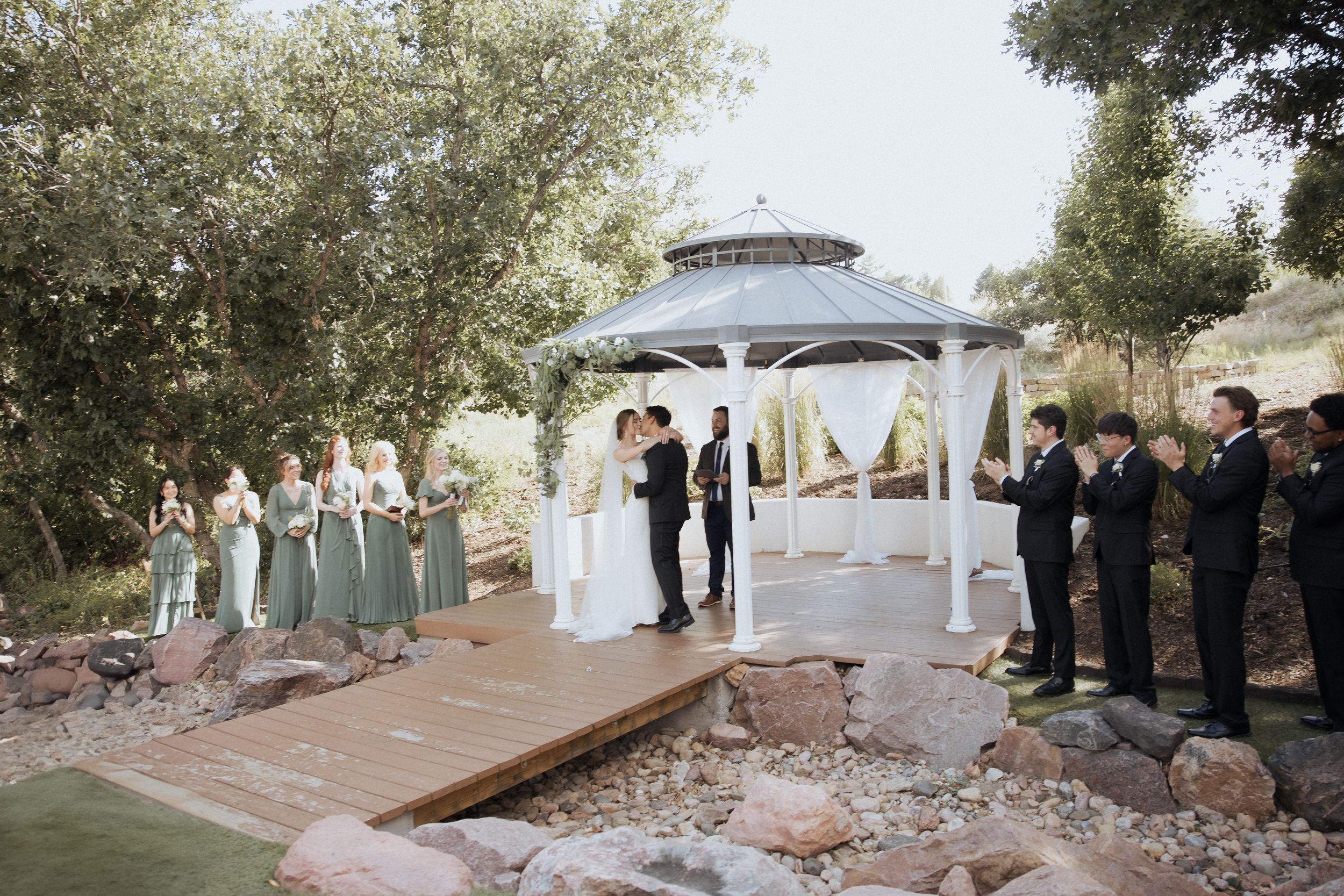 Outdoor wedding ceremony setup with white fabric draped gazebo and wooden benches overlooking a scenic desert landscape.