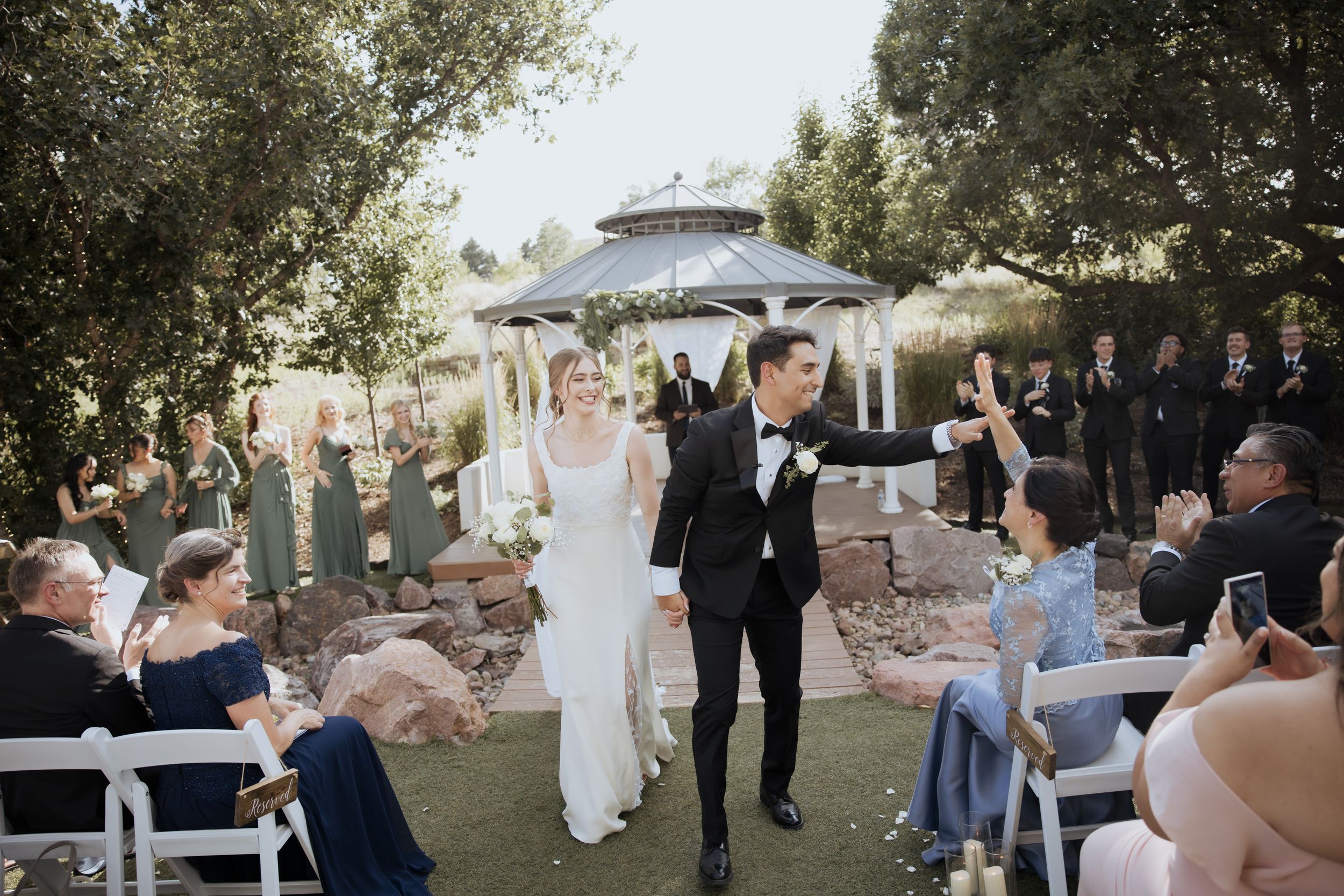 Wedding guests celebrate and dance together on an outdoor patio during a festive reception party.