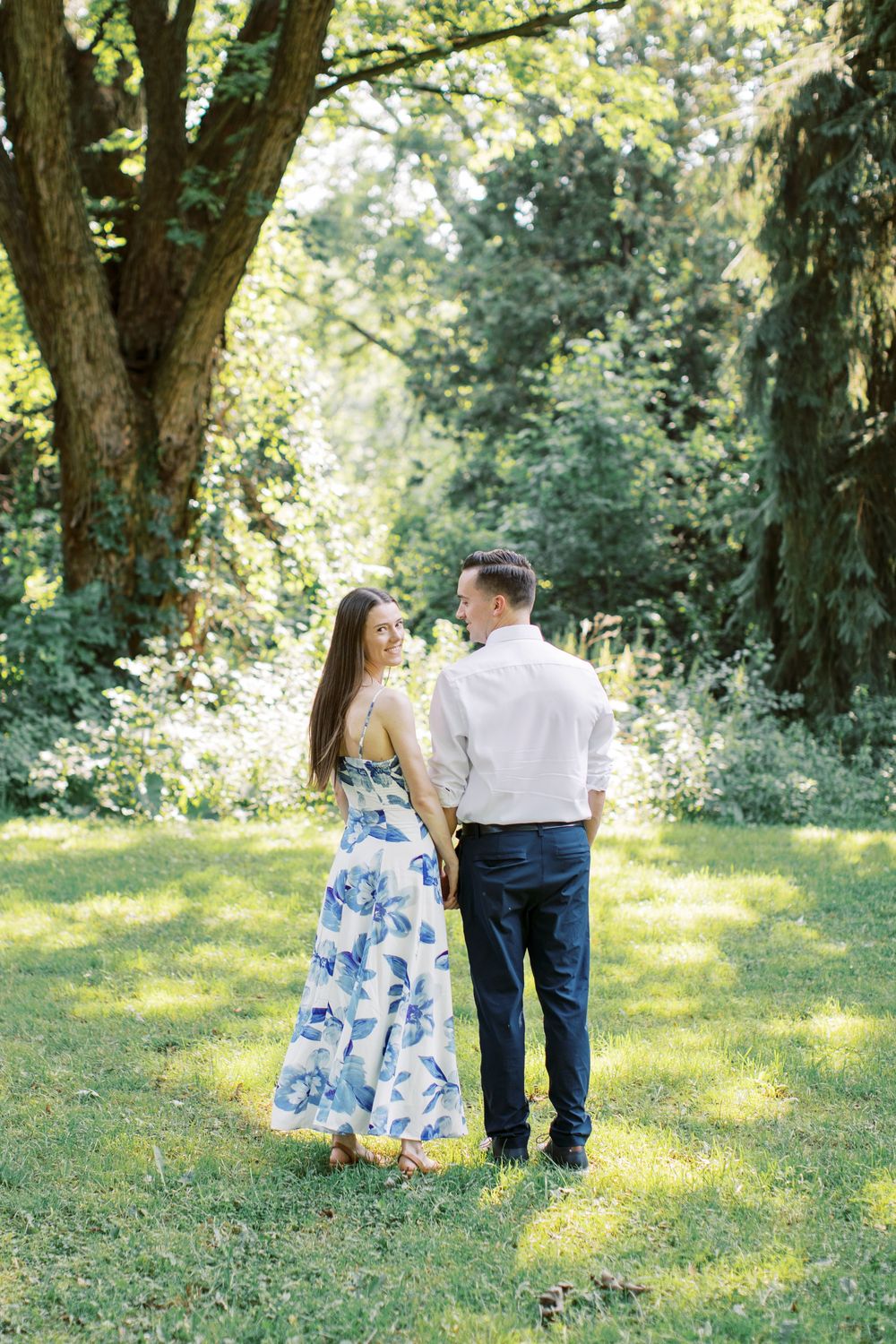 Couple in formal wear standing together in sunlit garden setting.