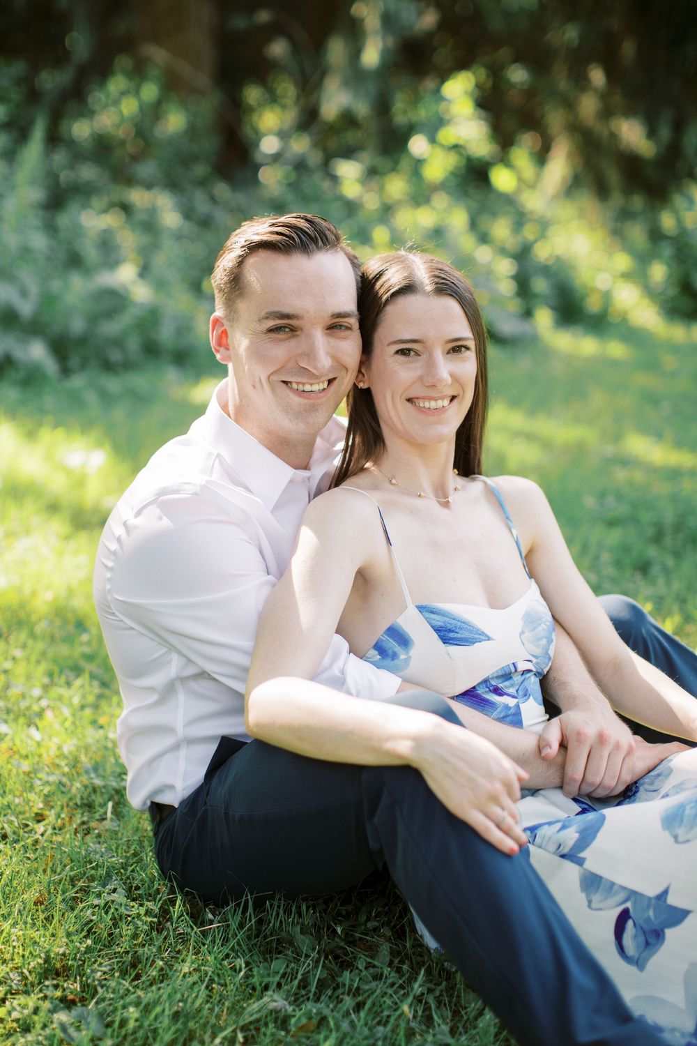 Couple enjoying a tender moment together on grass during a sunny day.