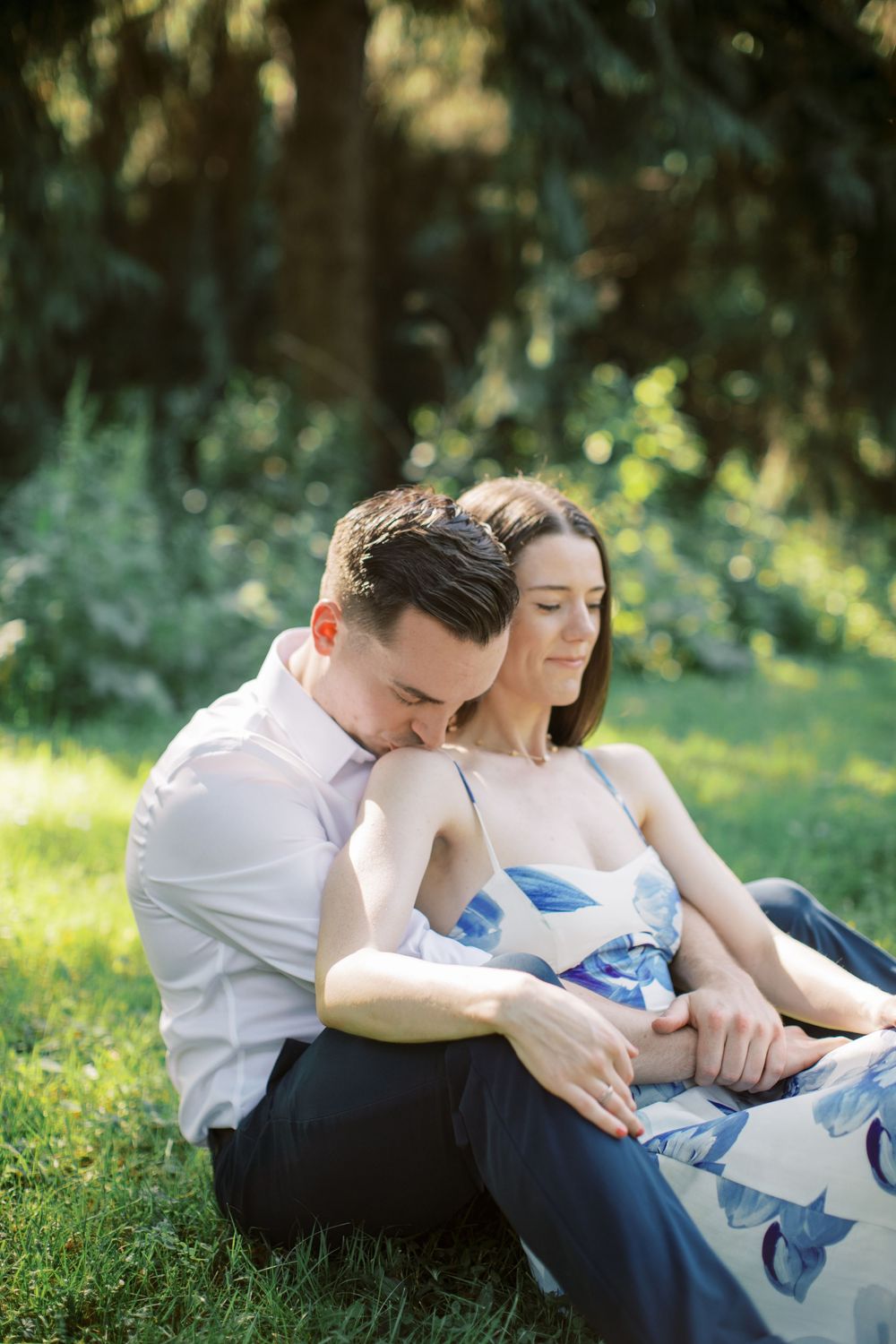 A couple relaxes together on green grass in a romantic outdoor photoshoot.