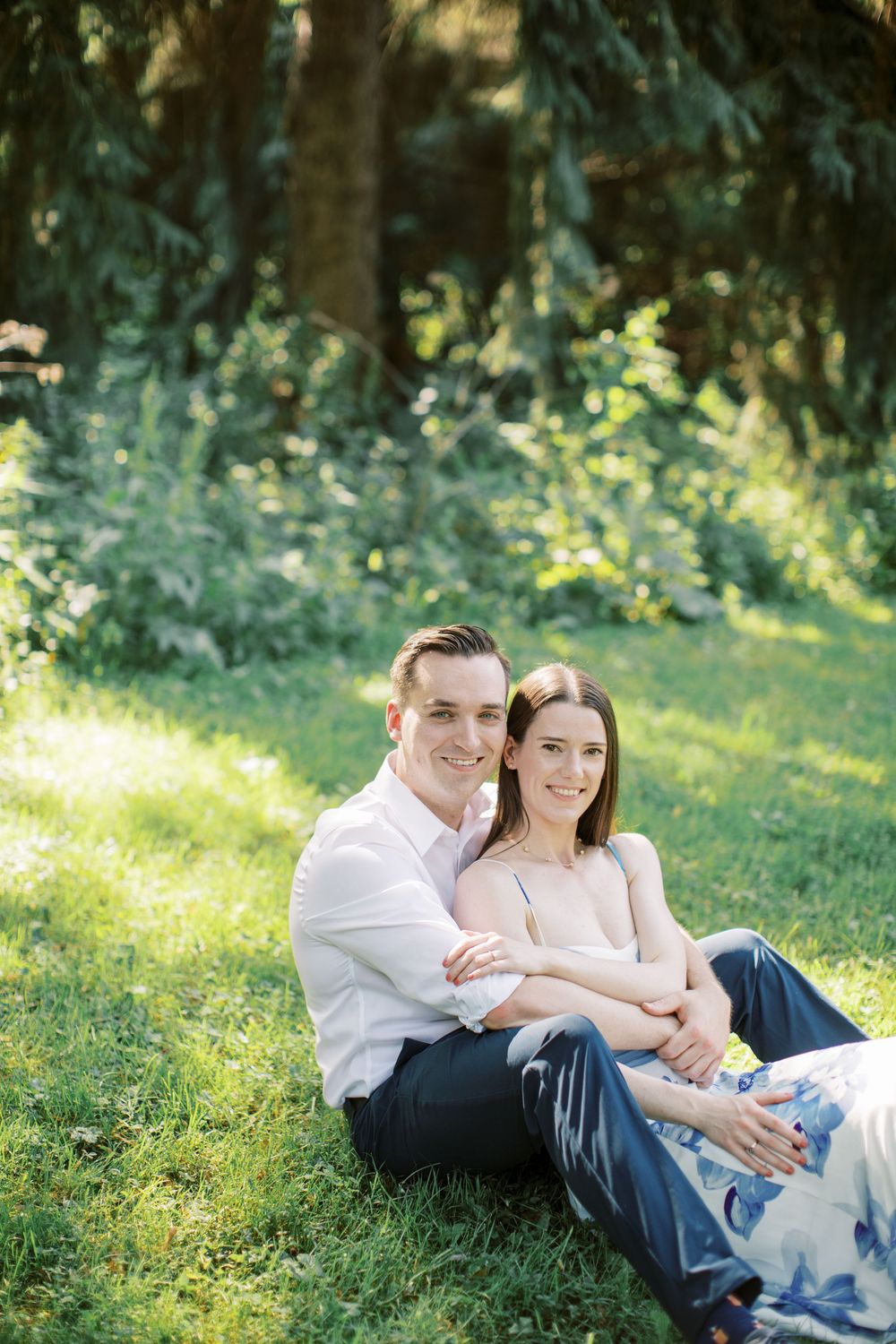 Intimate outdoor portrait session showing a couple laying in sunlit grass.