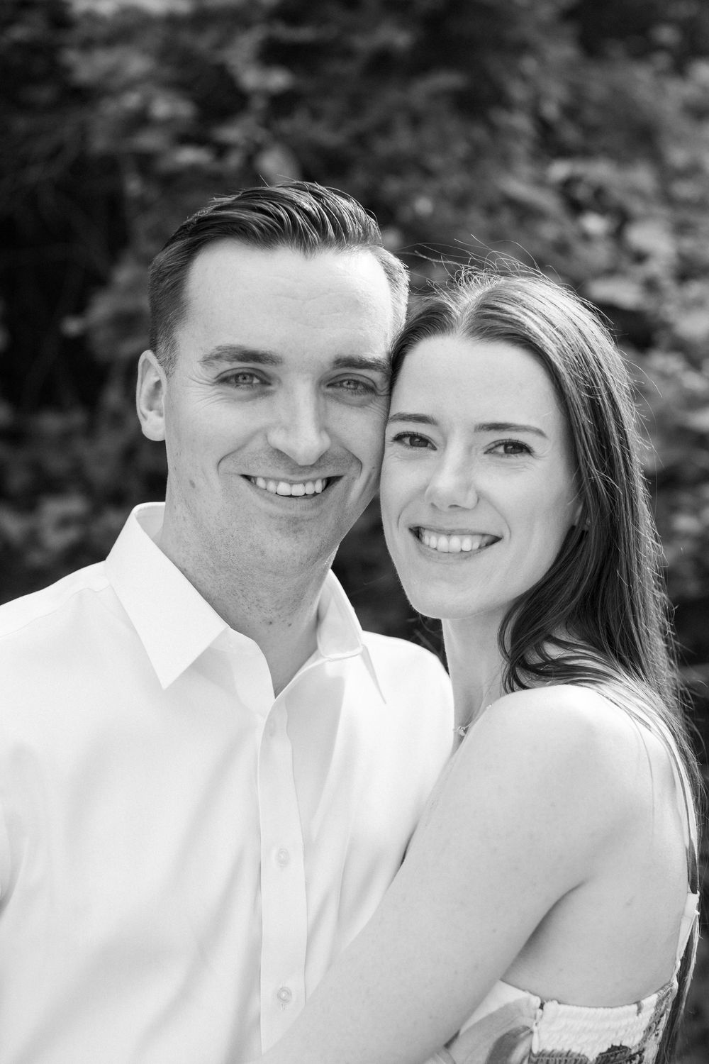 Black and white close-up portrait of a happy couple in matching white outfits.