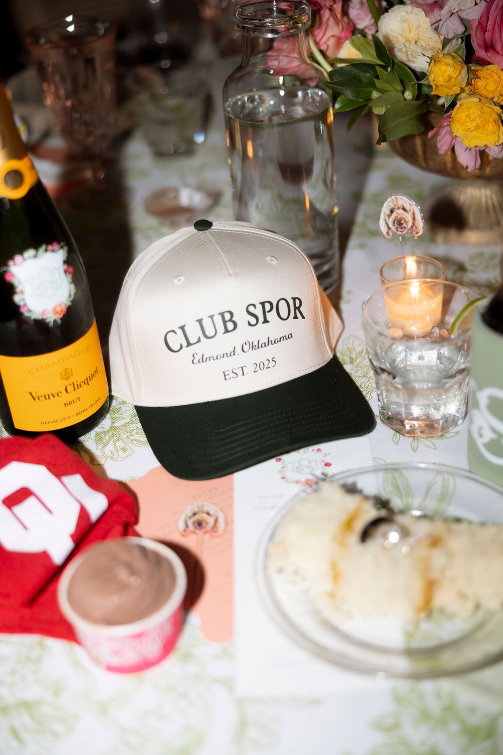 Wedding reception table settings with branded baseball caps and floral centerpieces.