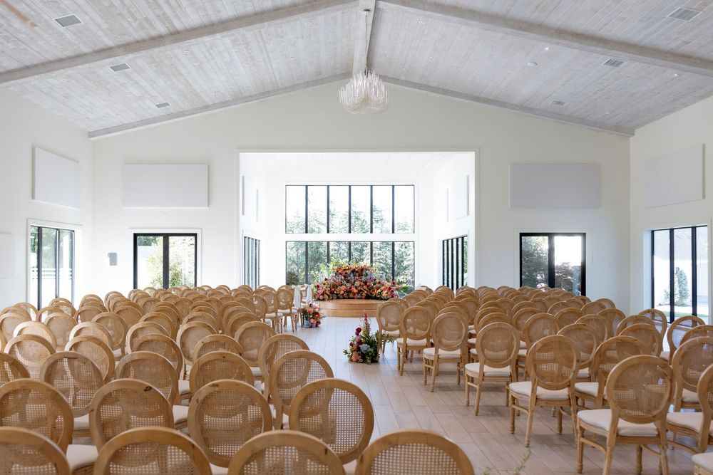 Clean, bright wedding ceremony space with rows of natural wood chairs in an all-white room.