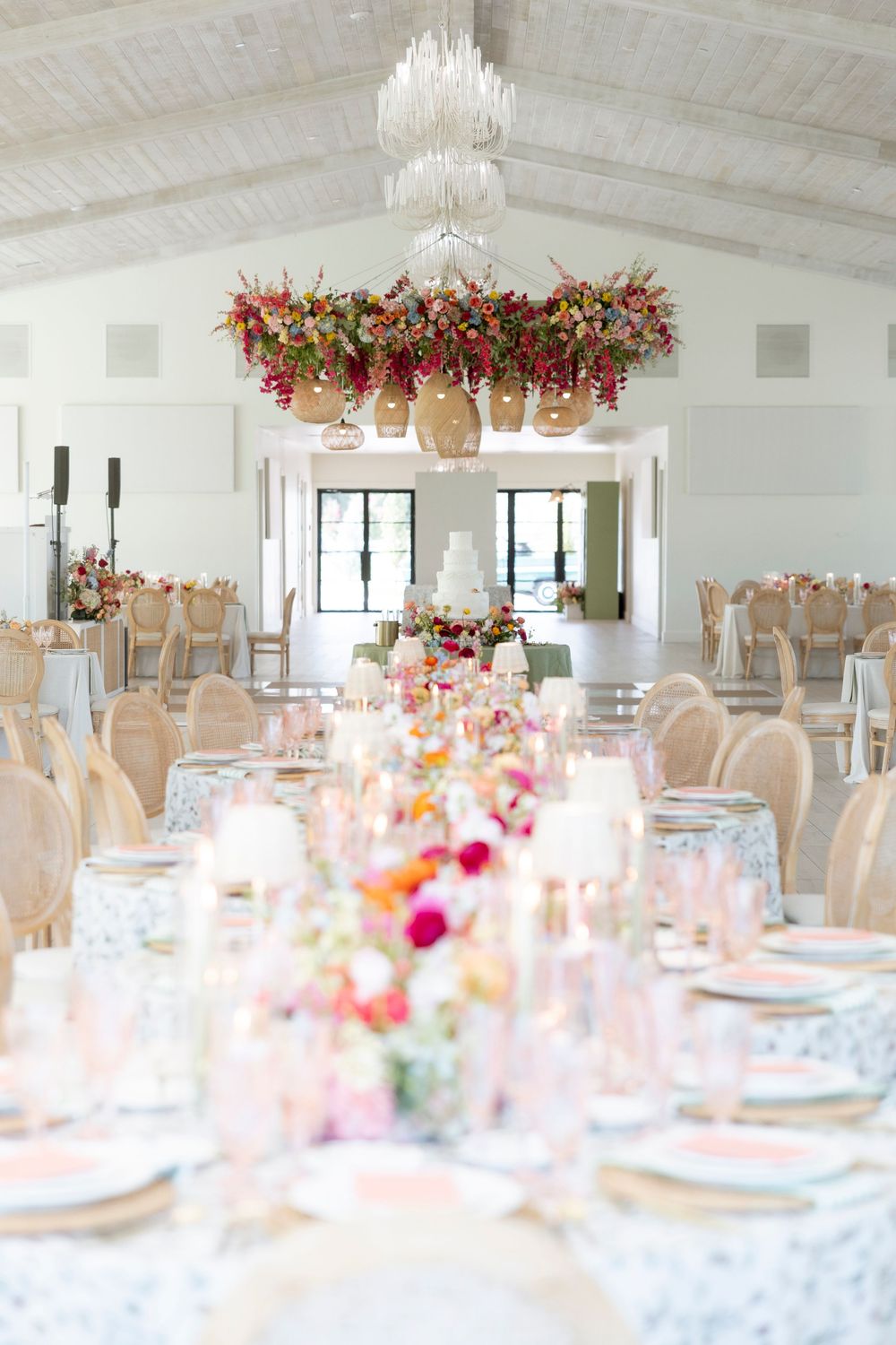 Elegant wedding reception venue with white tables, floral chandeliers, and romantic lighting creating a dreamy atmosphere.