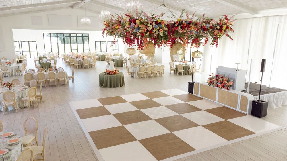 Spacious wedding venue with checkered floor and stunning floral chandelier installation.