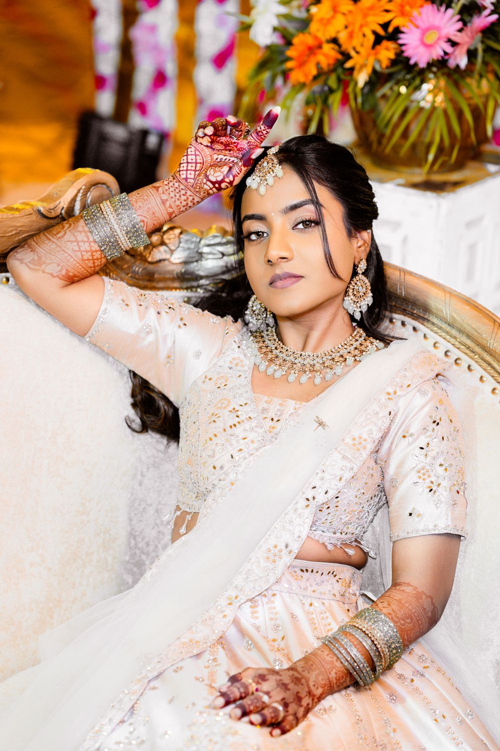 Traditional Indian bridal portraits showing intricate mehndi designs and white embroidered dress against floral backdrop.