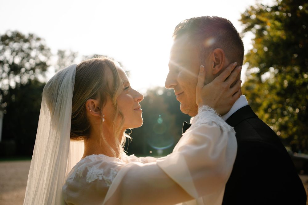 Bride holding grooms neck during golden hour couple portraits at a Hampshire wedding Pylewell park