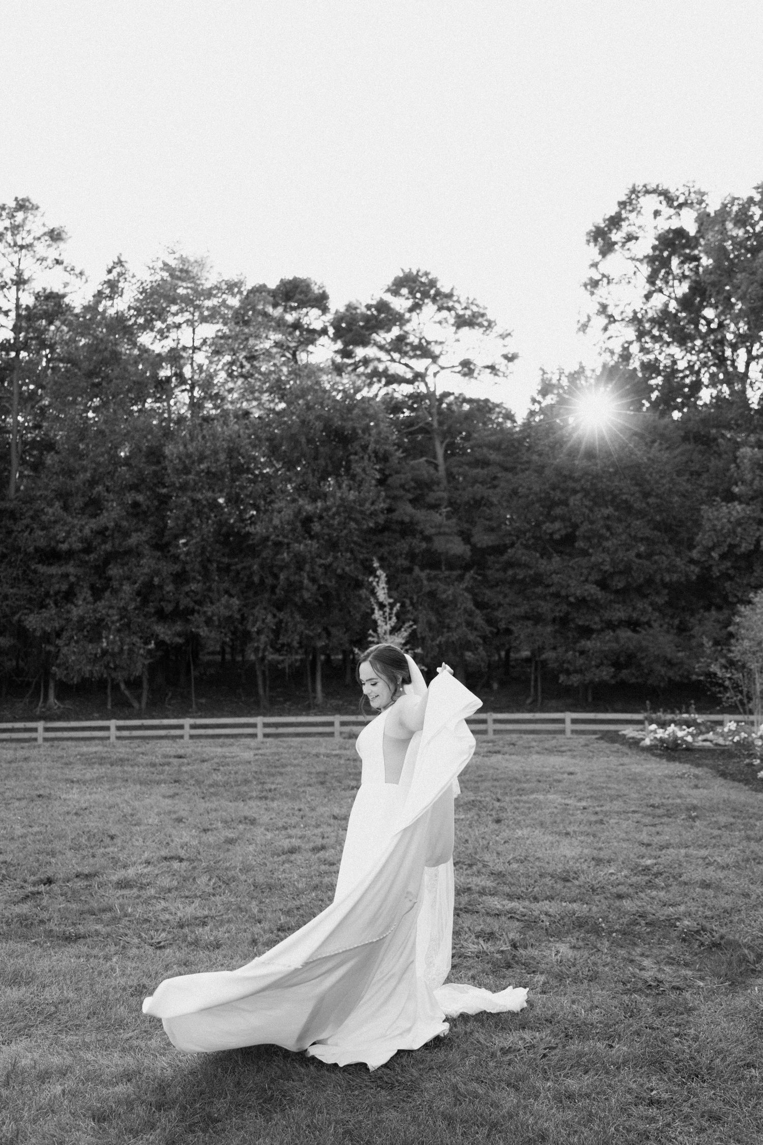 A flowing white dress billows dramatically in the wind across a pastoral field at sunset.