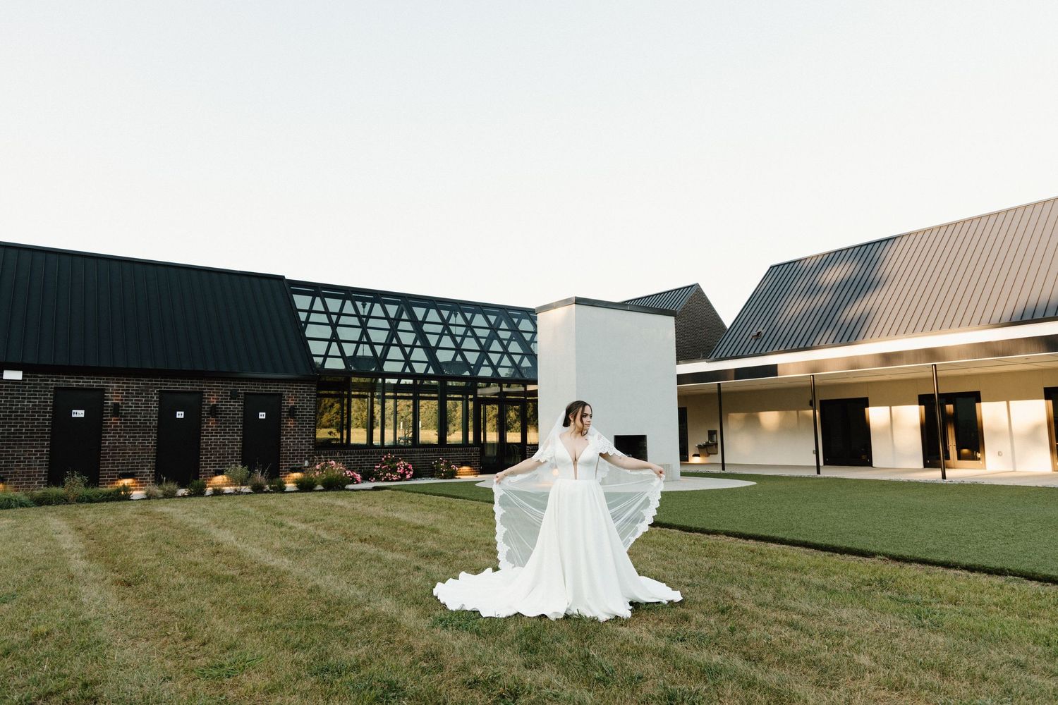 A modern black angular building with glass walls and geometric architectural details stands against a cloudy sky.