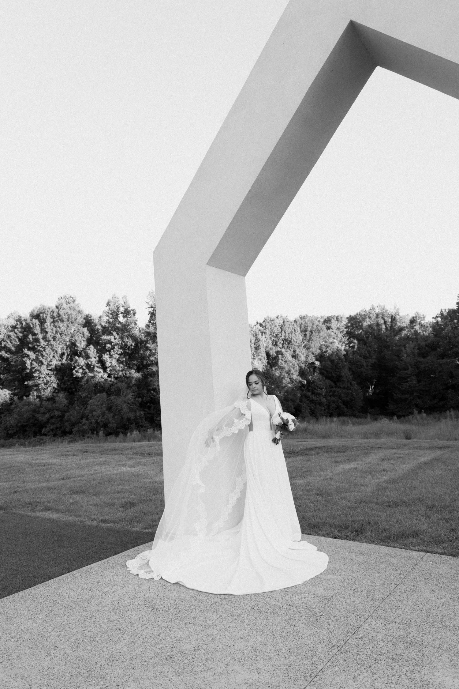 A series of black and white wedding photos showing the bottom of a flowing white dress against architectural elements.