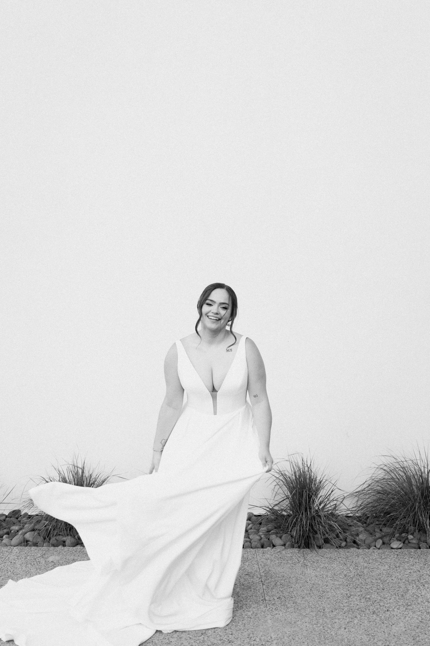 A person in a flowing white dress poses gracefully in a black and white outdoor portrait series.