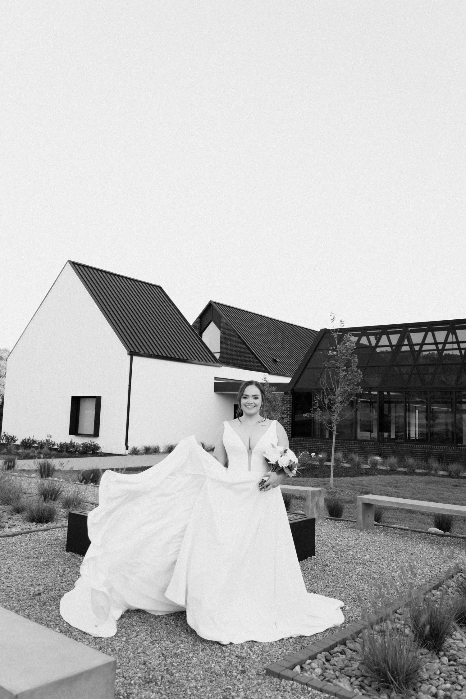 A series of black and white wedding photos showing a bride's flowing white dress in an outdoor architectural setting.