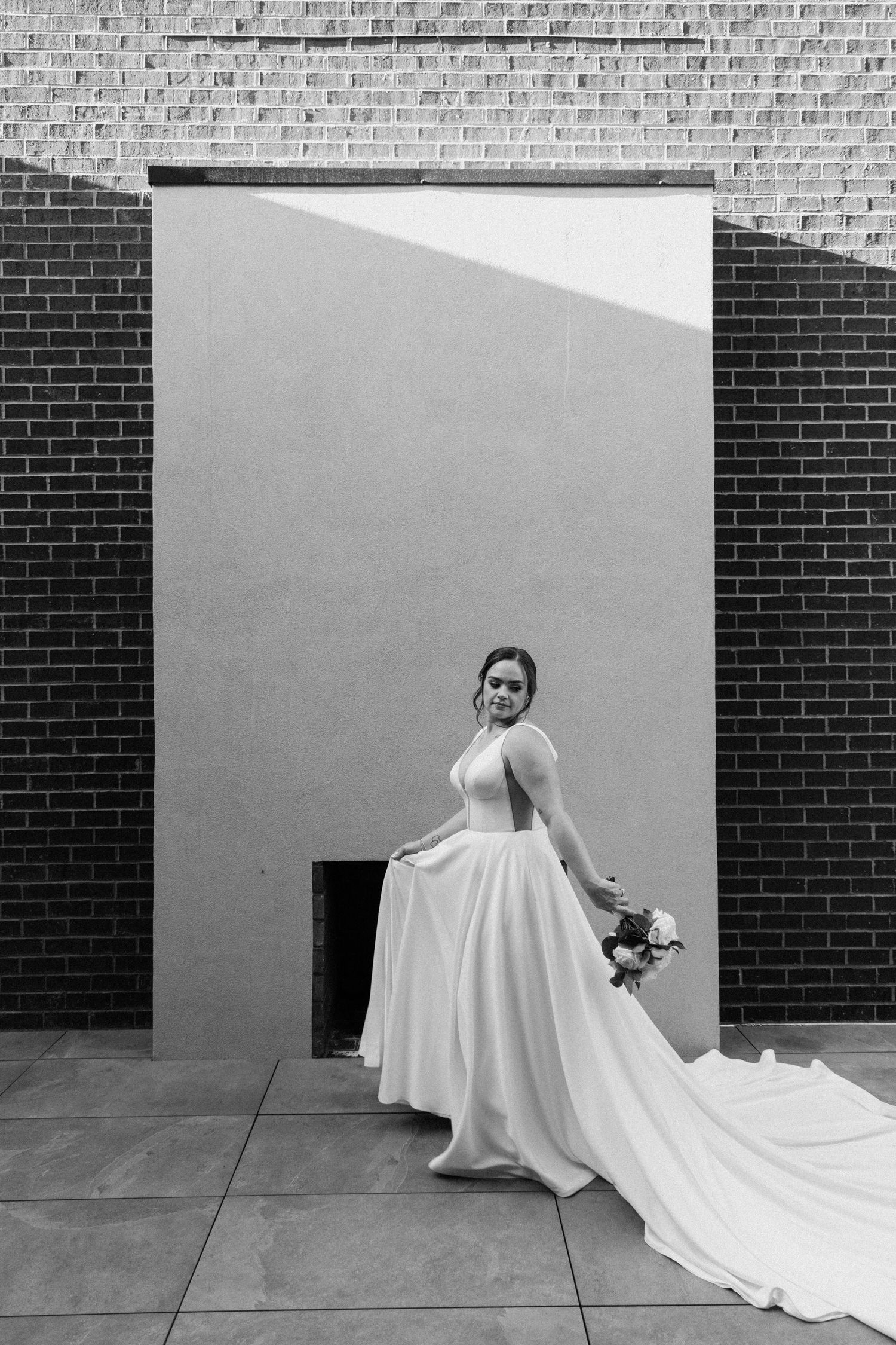 A series of black and white photos showing a flowing white wedding dress train against a brick wall backdrop.