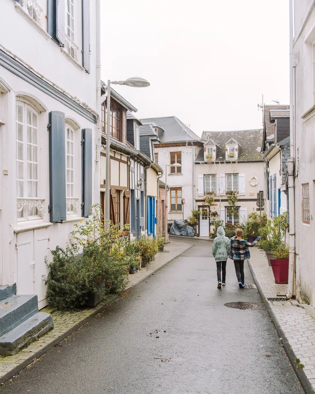 Family walking along a quaint European village street lined with pastel houses.