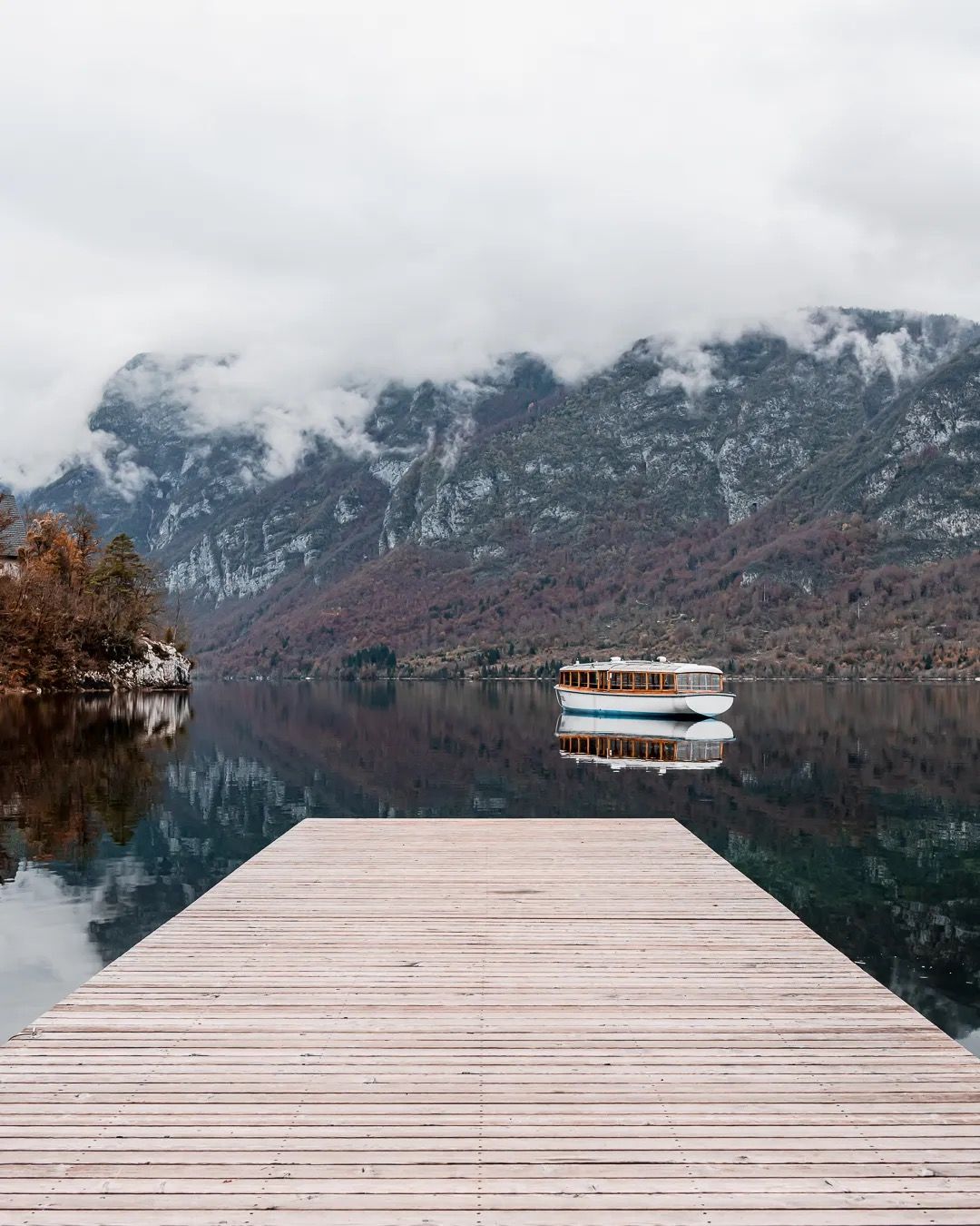 Infinity pool overlooking mountains and trees on a cloudy autumn day.