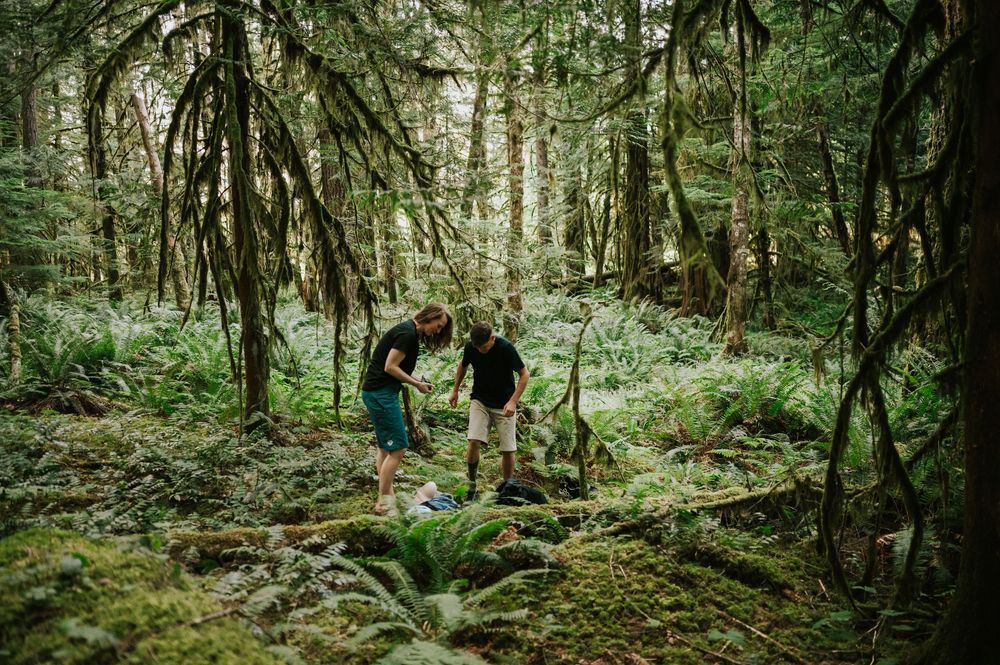 Adventurous couple engagement session photo of couple putting on biking socks in Cumberland Forest Vancouver Island